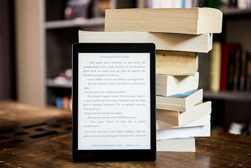 E-book reader and stack of paperback books